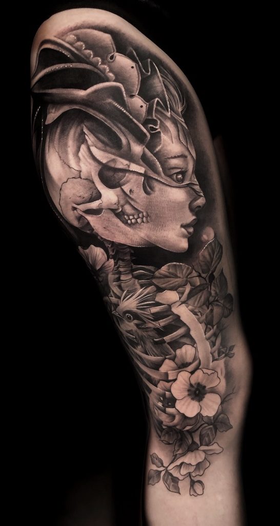 Tatuaje black and grey de rostro femenino, calavera y flores en pierna